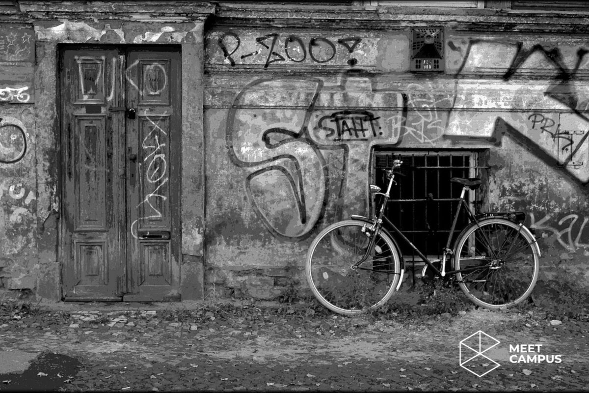 Ein schwarz-weiß Bild einer Hausfassade mit Graffiti und einem Fahrrad