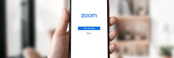 Es wird ein Smartphone in die Kamera gehalten auf dessen Display die Zoom-Seite zu sehen ist