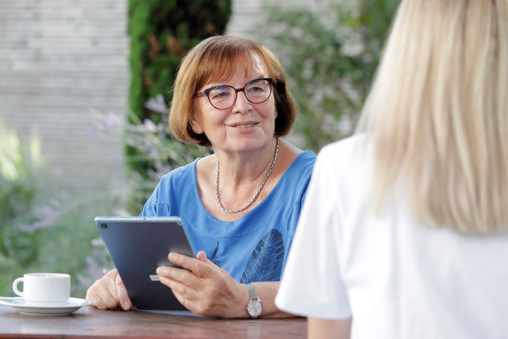 Frau mit Brille im Gespräch mit Tablet in der Hand